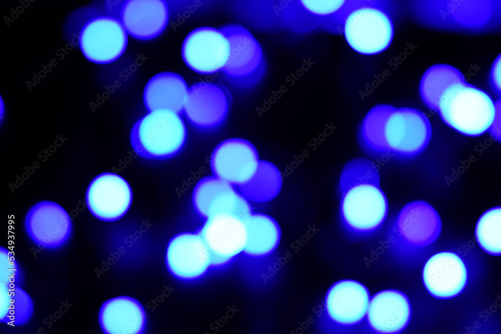 Blue circle bokeh lights blur the pitch dark background.
