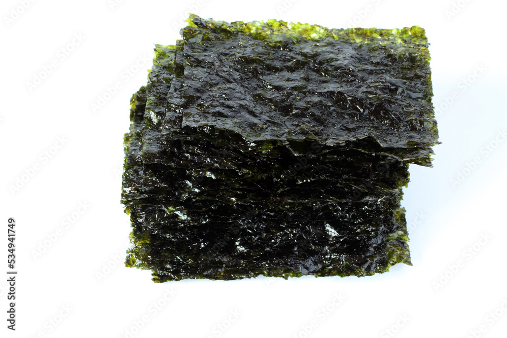 Seasoned seaweed snack. Algae sheets stacked in a pile on white background. Seasoned seaweed snack. Algae sheets stacked in a pile on white background.