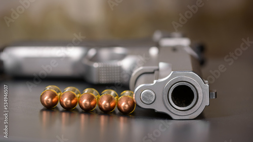 Semi automatic stainless steel short gun and copper bullets 9 mm on natural light. photo