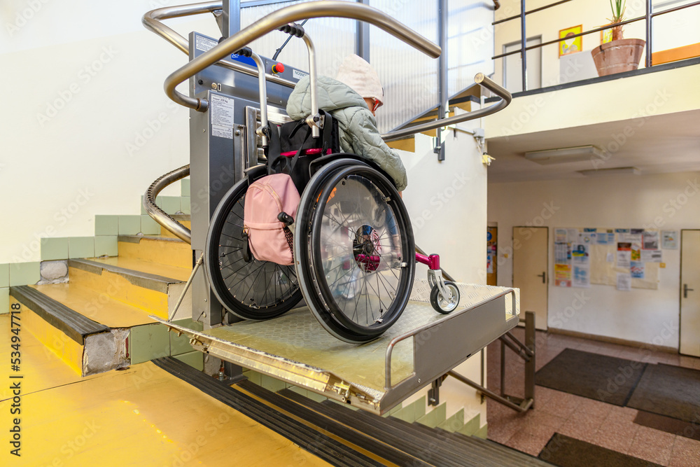 Young child living with cerebral palsy using electric wheelchair lift