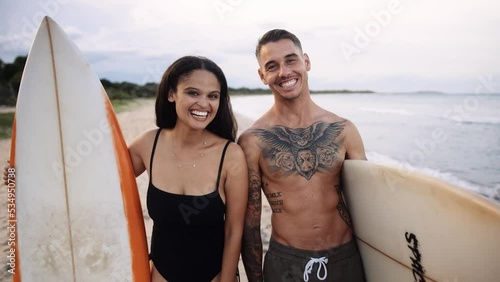 Happy young couple with surfboards kissing on beach by sea