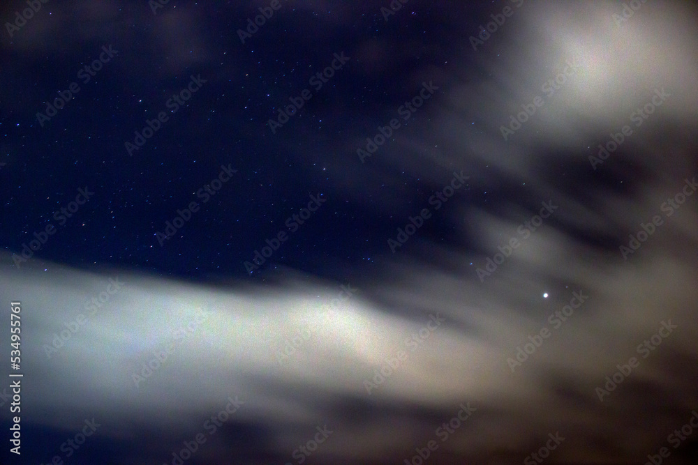 Night sky with passing clouds and stars in long exposure