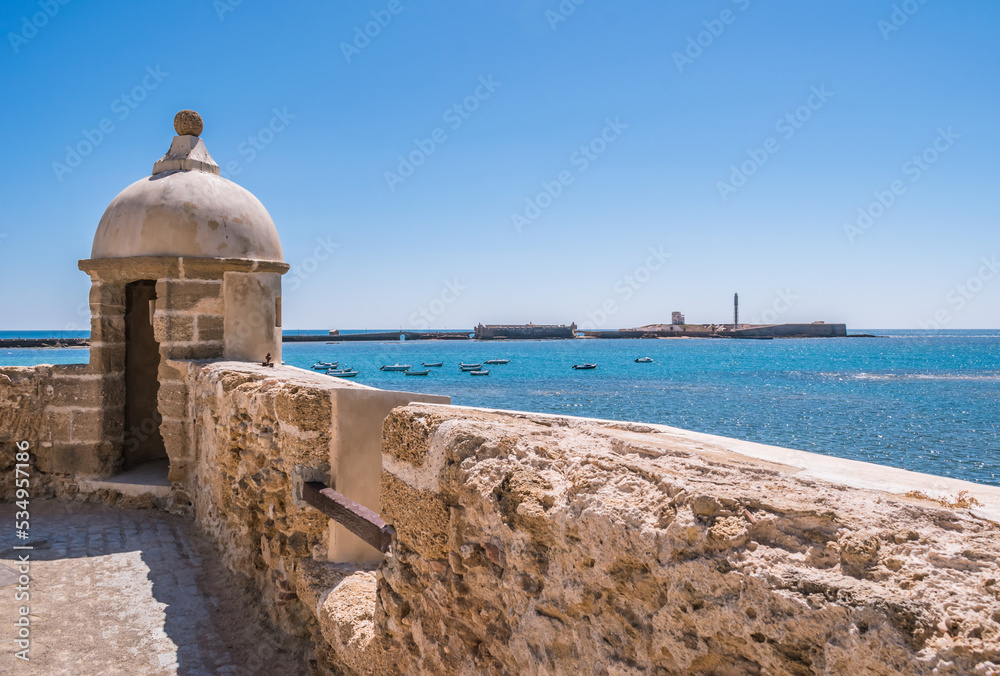 Fototapeta premium Wall and guardhouse in perspective at Santa Catarina fort with San Sabastian castle in the background on small island, Cádiz SPAIN