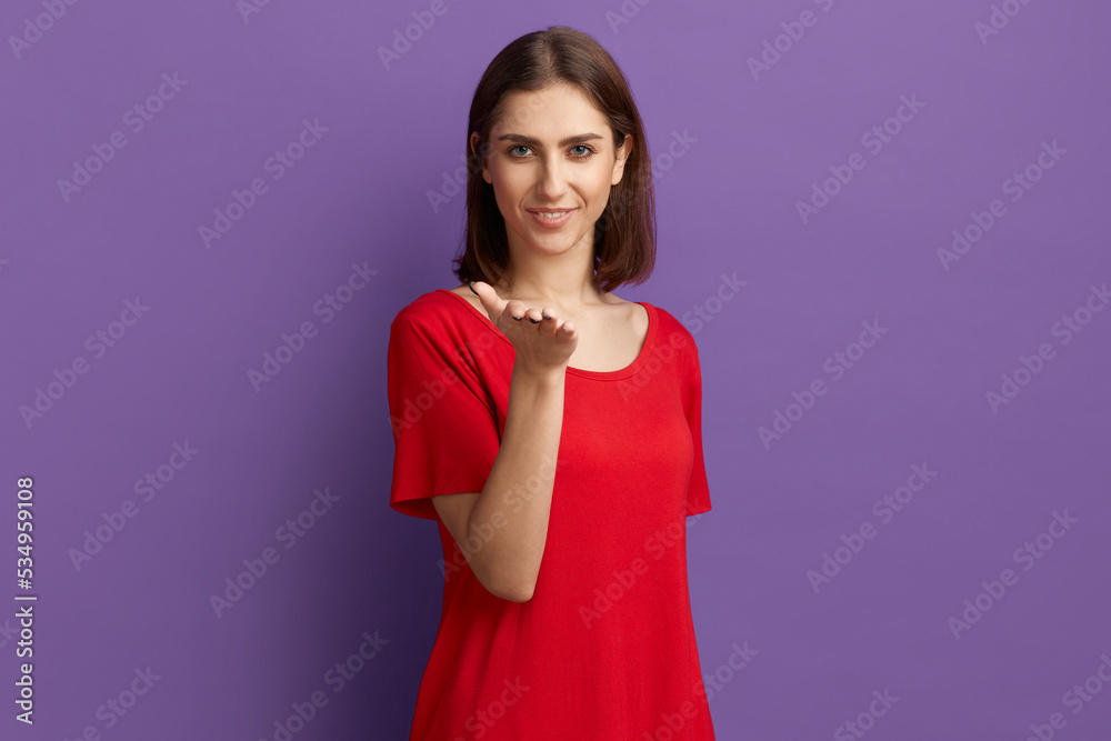 Wait for true feelings. Pretty brunette girl in red t-shirt blows air kiss, holds palm near mouth and looking at the camera with a charming smile. Flirt and love emotions. Posing over purple wall. Wait for true feelings. Pretty brunette girl in red t-shirt blows air kiss, holds palm near mouth and looking at the camera with a charming smile. Flirt and love emotions. Posing over purple wall.
