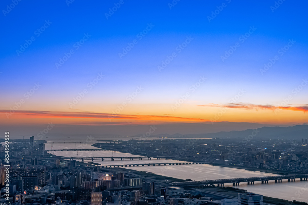 沈み行く夕陽に照らされる大阪の街並みと淀川【大阪風景】