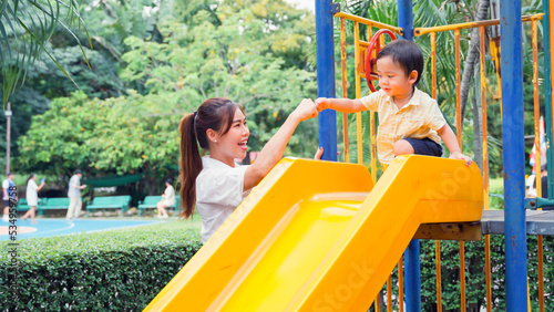 Mother encourage the little boy her by fist bump before the little son will play slides.