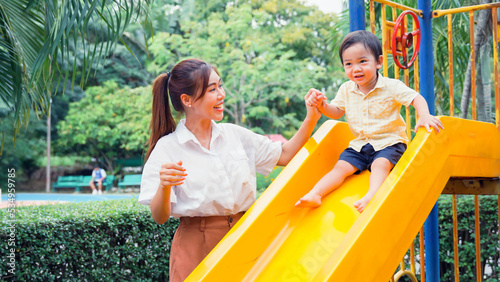 Mother encourage the little boy her by high five before the little son will play slides. © P Stock