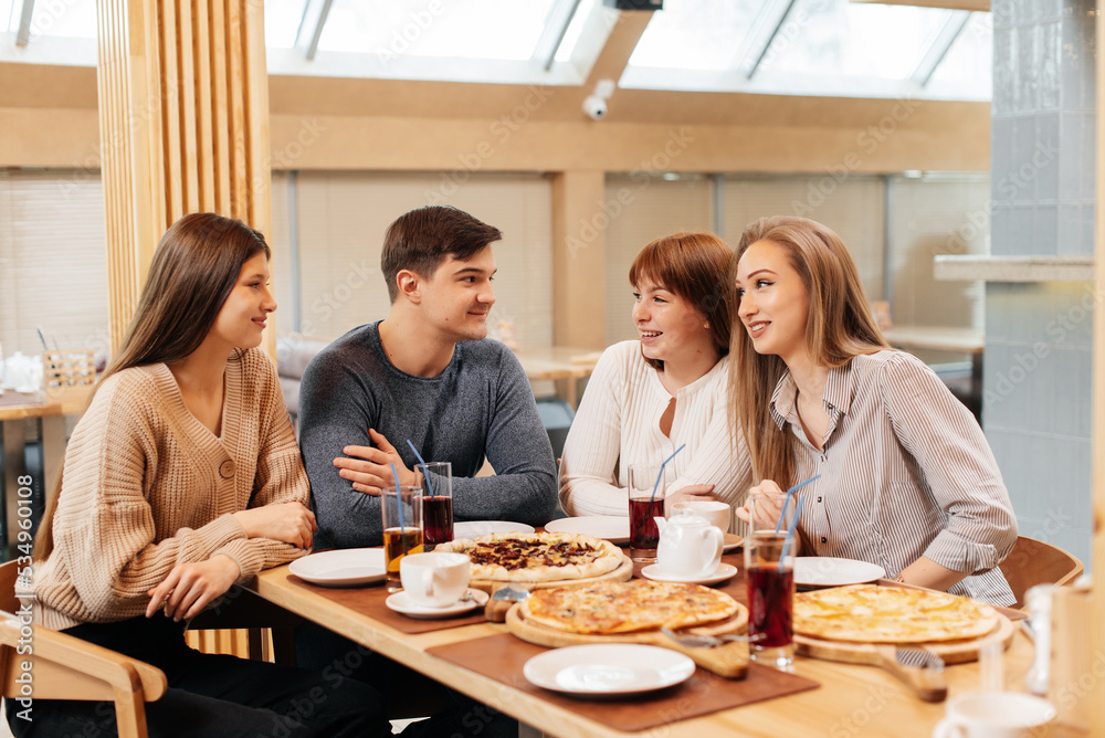 A group of friends is having pizza in a cozy restaurant. Meeting friends over dinner, socializing with a friendly company. A group of friends is having pizza in a cozy restaurant. Meeting friends over dinner, socializing with a friendly company.