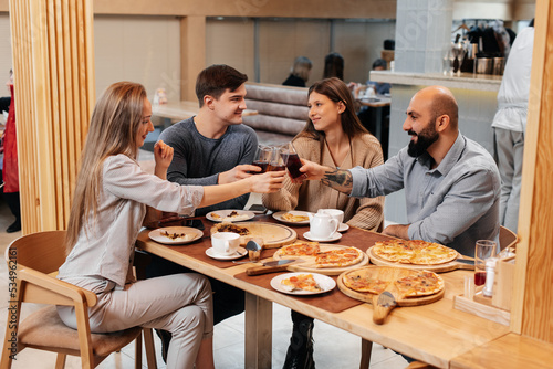 A cheerful group of friends is eating delicious pizza in a restaurant. Friends are sitting in a restaurant and having fun.