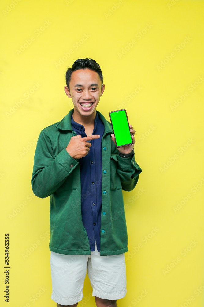 a man wearing a blue shirt with a green jacket and white pants making an expression with his smartphone, on a yellow background a man wearing a blue shirt with a green jacket and white pants making an expression with his smartphone, on a yellow background
