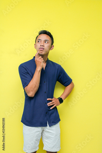 man in blue shirt and white pants thinking about something, on a yellow background © Arif