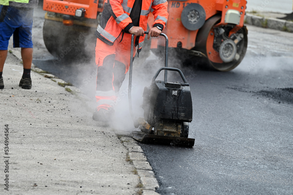 A plate compactor for compacting asphalt at a road construction site A plate compactor for compacting asphalt at a road construction site