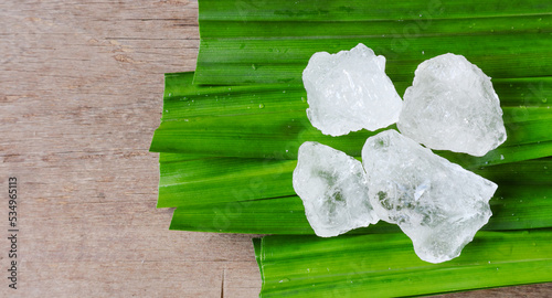 Crystal clear alum cubes or Potassium alum on green leaf. Chemical compound substance. Concept for beauty , spa and underarm treatment industrial.                                