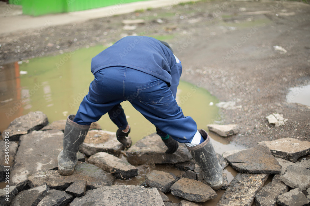 Worker collects stones. Guy cleans up construction debris. Broken asphalt. Worker collects stones. Guy cleans up construction debris. Broken asphalt.