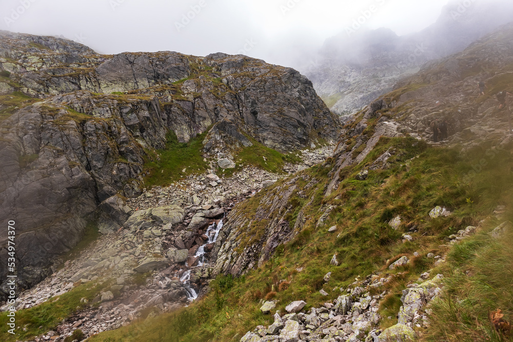 Impressive landscape with large grey-brown mountains in the Polish Tartars with a rocky hiking path and green grass