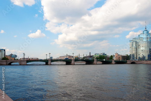 A large majestic stone bridge over the river in the city against a cloudy sky. A clear sunny summer day