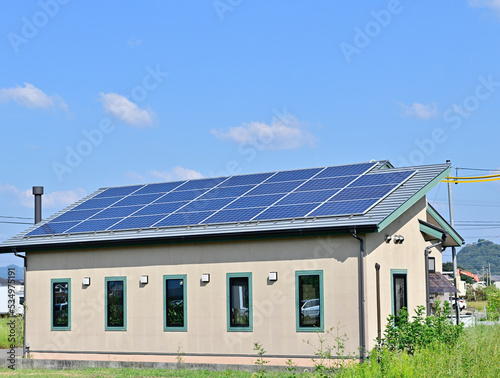 太陽光パネルが設置された住宅の屋根と快晴の青空。