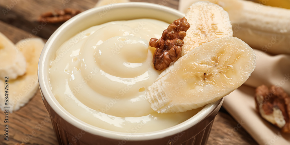 Bowl of delicious vanilla pudding with banana and nuts on table, closeup Bowl of delicious vanilla pudding with banana and nuts on table, closeup