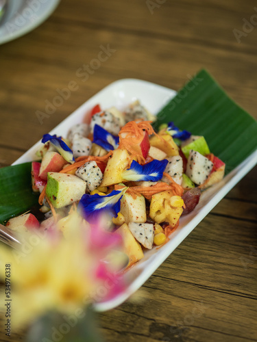 Thai Mixed Fruits Salad Served in a rectangular white ceramic dish. The selective focus.