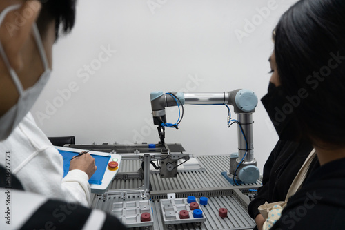 Asian Student study Robotic Arm with Screwdriver During the Lesson. Robot is Moving. Computer Motherboard Components at Digital Interactive Whiteboard at Background. Education Concept
