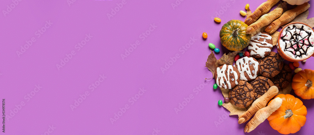 Halloween cookies, autumn leaves, pumpkins and drink on violet background with space for text