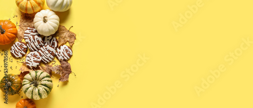 Halloween cookies, pumpkins and autumn leaves on yellow background with space for text
