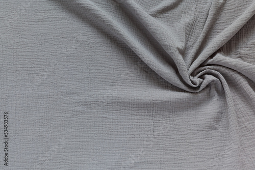 Stylish cotton wrinkled muslin fabric. Gray textile background. Base for sewing breathable, light, fashionable clothes. Empty space for text. Flat lay, close-up, top view, copy space, mock up