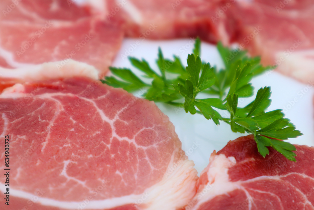 Raw Pork Slice in White Round Plate decorated with parsley. Fresh raw pork.