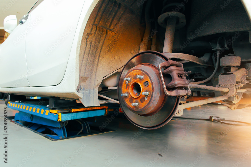 Rear disc brakes and calipers that remove the wheels of a car in the auto repair garage with sunlight