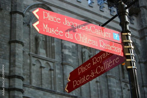 Road Signs of Montreal City, background is Notre-Dame Basilica of Montreal. Four signs means respectively: Place Jacques-Cartier, Museum of the Château Ramezay, Royal Square, Pointed to Calliere  photo