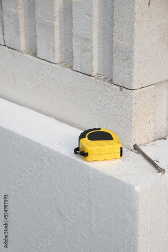 thermal insulation house. Black yellow tape measure on white rigid polyurethane foam sheet on wall. 