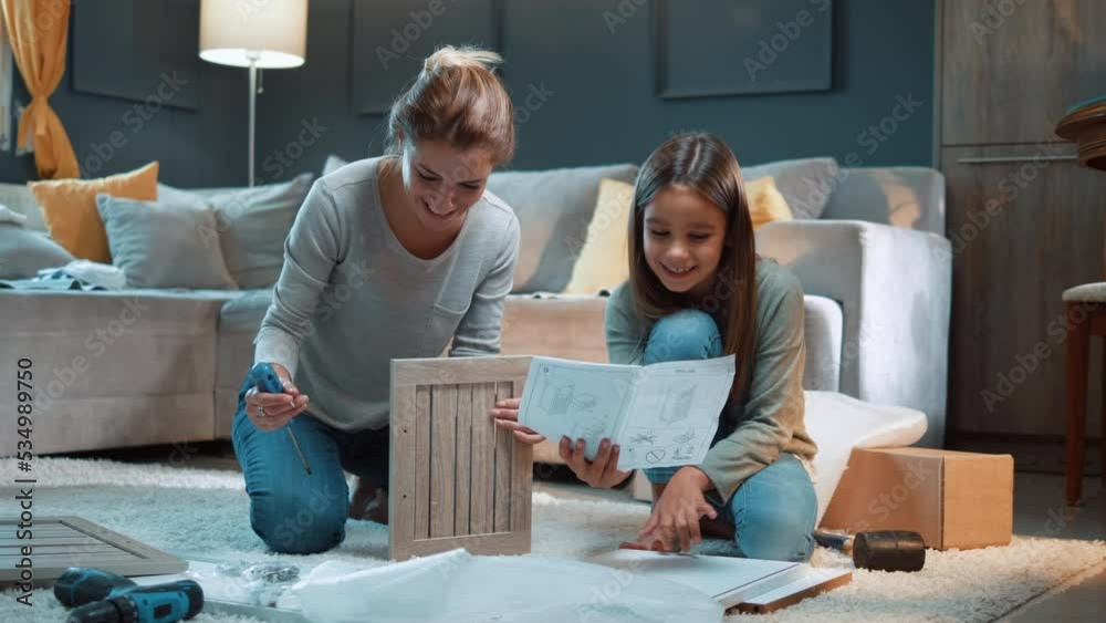 Happy family assembles furniture as a team, daughter reads instructions and mother follows