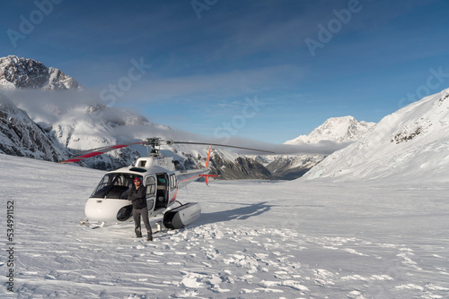 Man posing in front of a helicopter on a sunny morning along the Tasman Glacier in the Southern Alps of New Zealand.