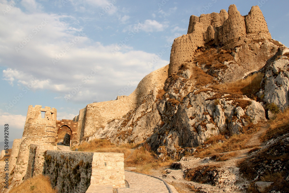 View of the old part of Van Castle, which is located on a high rock, with an entrance gate, against a blue sky with clouds, in the Eastern Anatolia region, Turkey