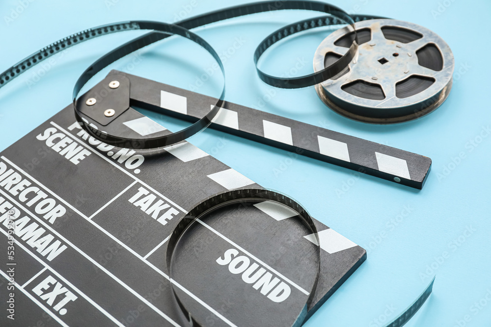 Movie clapper with reel on blue background, closeup