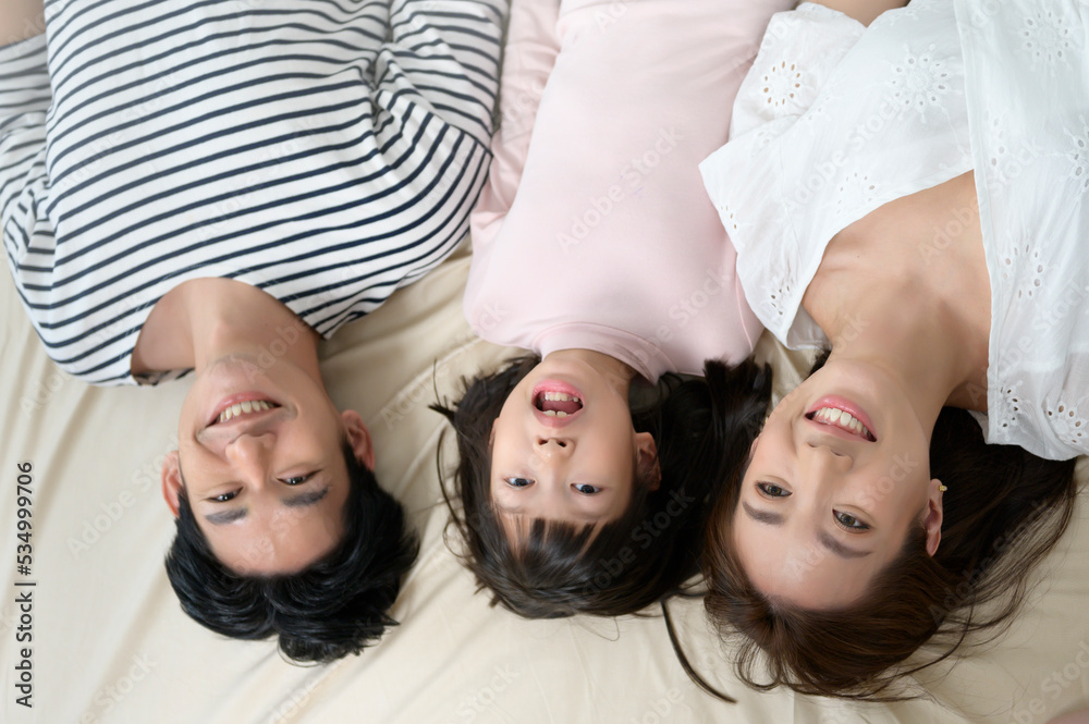 Top view of asian Parents with little daughters on the bed in bedroom, happy family concept