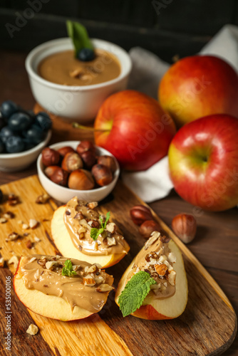 Board of fresh apple wedges with nut butter on wooden table  closeup