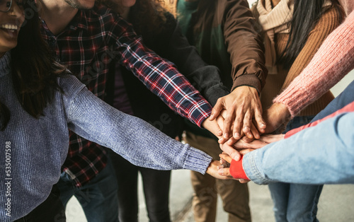 Happy young friends having fun stacking hands together outdoor - Youth people millennial generation concept