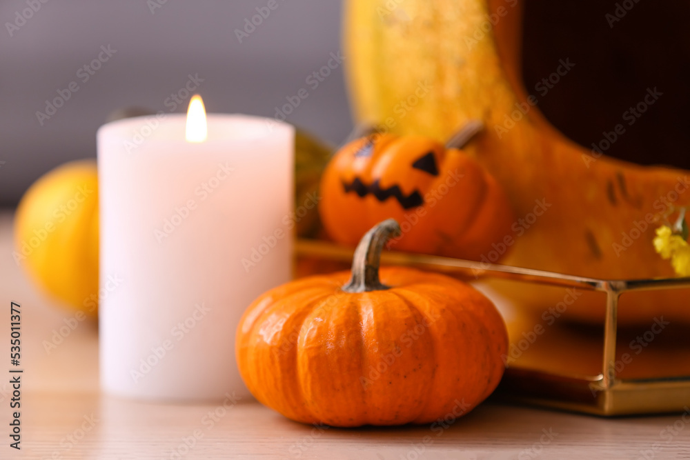 Halloween pumpkins with burning candle on table in room, closeup Halloween pumpkins with burning candle on table in room, closeup