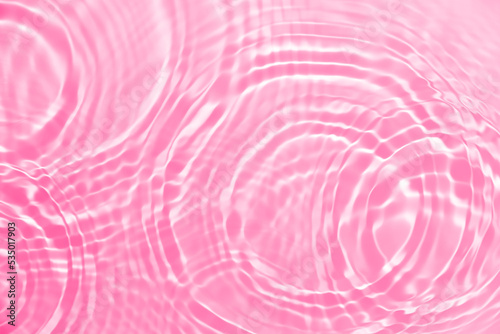 Rippled water background with circles and splashes. Pink, coral abstract texture