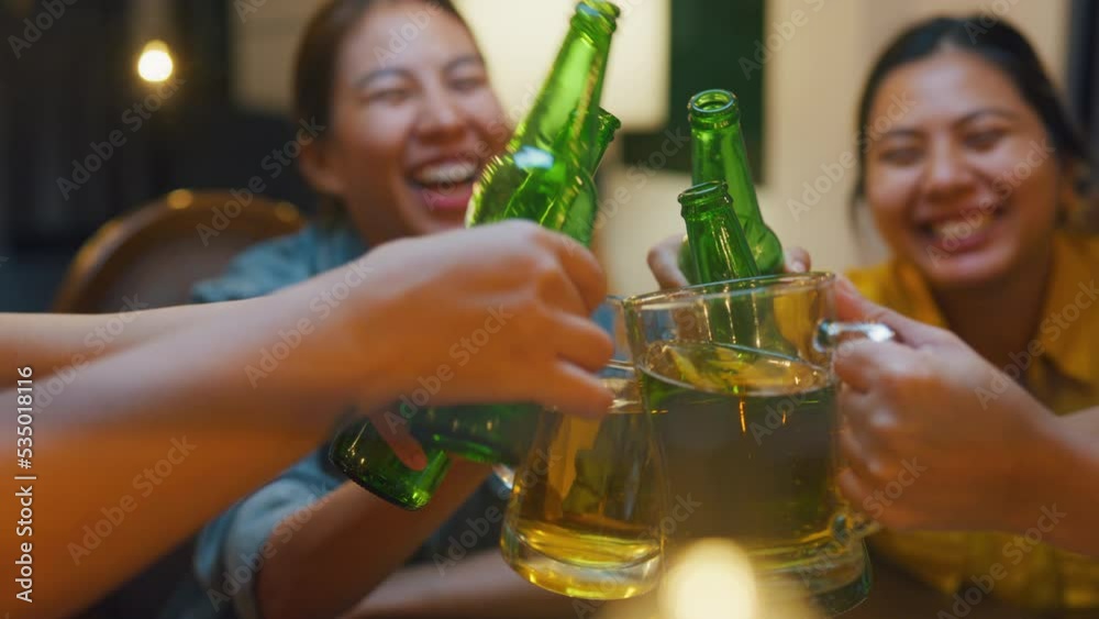 Closeup of Group of multiethnic adult Asia friend drinking alcohol beer bottle glass and having fun laugh enjoy hangout party in night life indoor home. Happy hour millennial generation inside house.