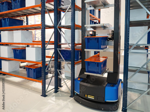 Automated warehouse processes. Modern warehouse with automated equipment. Robot picks up boxes from racks. Storage robot stands between racks. High-tech warehouse. Automated storage tech