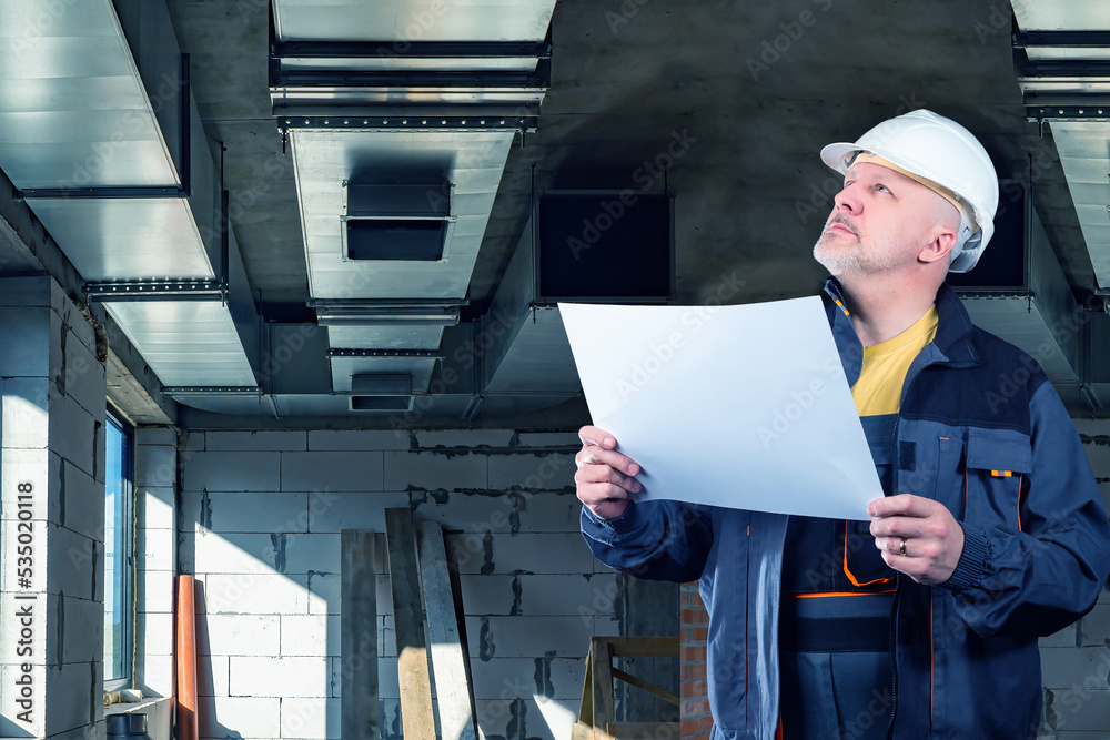 Design of ventilation system. Engineer man looks at ventilation pipes ...
