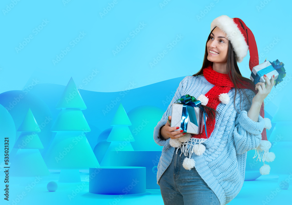 Obraz premium Christmas woman. Girl with gifts for New Year. Christmas woman is preparing for holiday. Girl in front of Christmas decorations. Young happy lady in Santa hat. Podium stand and XMas trees