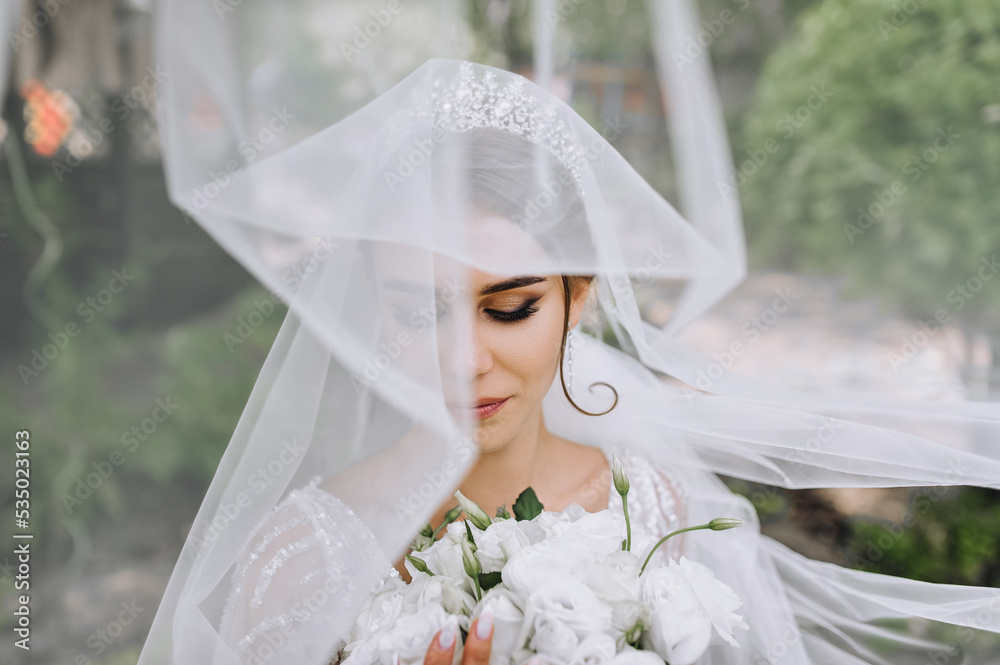 Close-up portrait of a beautiful bride model with a diadem on her head with a white long veil with a bouquet in her hands. wedding photography. Close-up portrait of a beautiful bride model with a diadem on her head with a white long veil with a bouquet in her hands. wedding photography.