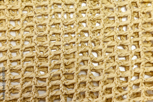 Texture of crocheted handmade of raffia threads straw colored.