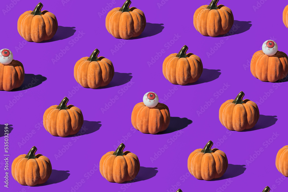 Pumpkins and eyeballs, creative arrangement on purple background. Halloween celebration inspired.