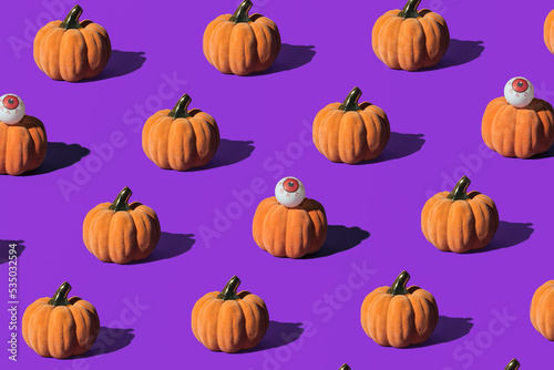 Pumpkins and eyeballs, creative arrangement on purple background. Halloween celebration inspired.