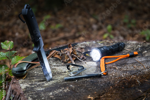 Several survival and bushcraft tools on a tree stump