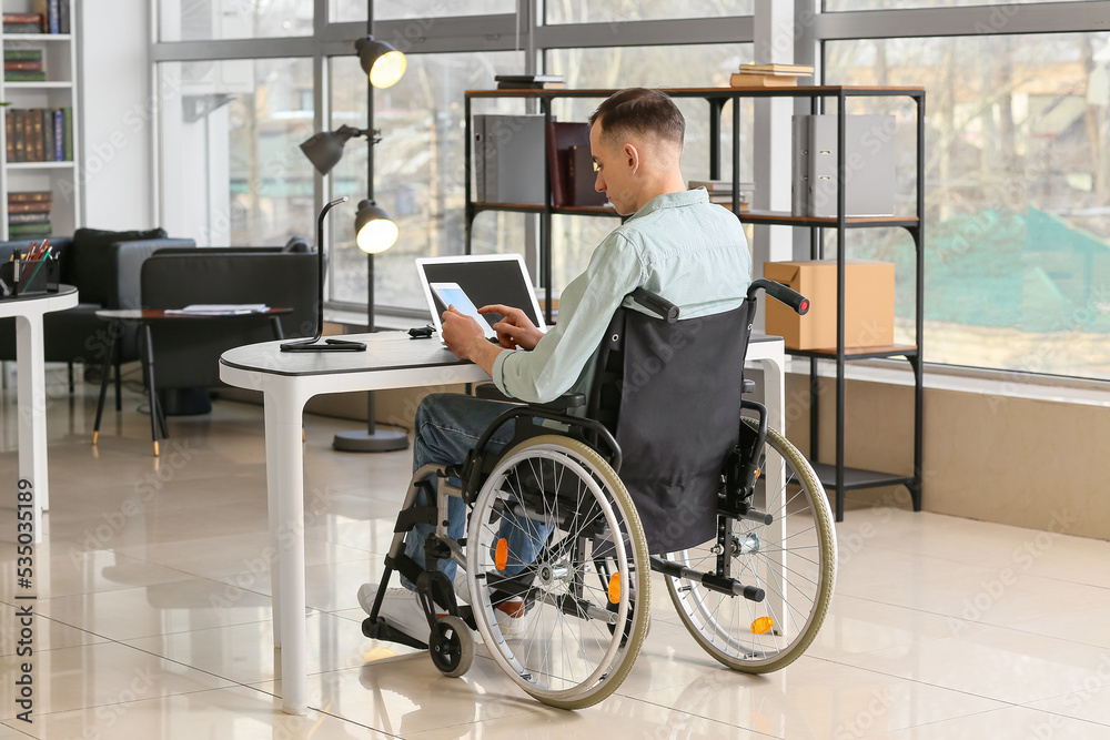 Young man in wheelchair working in office Young man in wheelchair working in office